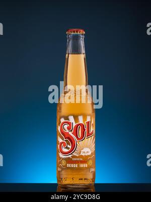 Istanbul, Turchia - 20 ottobre 2024: Primo piano della bottiglia Sol Beer su superficie nera lucida e sfondo blu Foto Stock