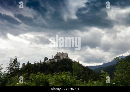 Paesaggio spettacolare prima del temporale con il castello medievale di Hohenwerfen sulla montagna boscosa. Scenario tempestoso con vecchio palazzo da nuvole scure cielo i Foto Stock