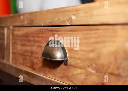Una vecchia tavola laterale rustica fatta a mano che mostra il cassetto in legno e una classica maniglia in ottone Foto Stock