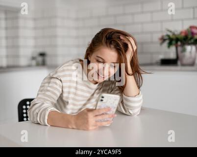 Cheerful Girl parla al telefono a casa in cucina Foto Stock