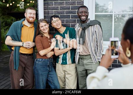 Gruppo multietnico di persone adulte che posa per scattare foto all'aperto e sorridono felici di godersi una festa con gli amici Foto Stock