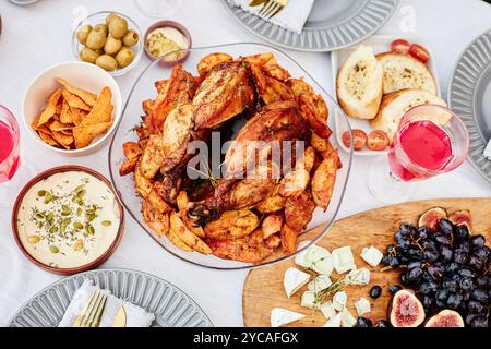 Vivace vista dall'alto sullo sfondo di delizioso pollo alla griglia con patate arrosto durante la cena di gala scattata con flash Foto Stock