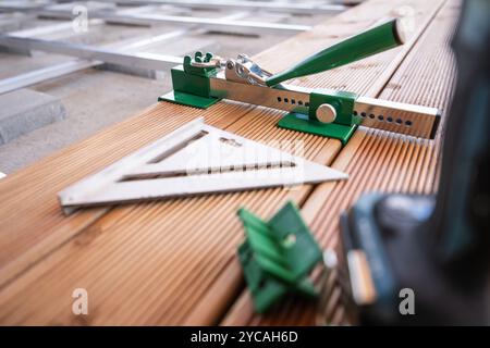 Vari utensili per carpenteria sono montati su tavole di legno, sottolineando la precisione di misurazione e allineamento durante un progetto di lavorazione del legno. Foto Stock