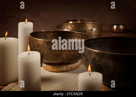 Ciotole cantanti tibetane con candele in fiamme da vicino Foto Stock