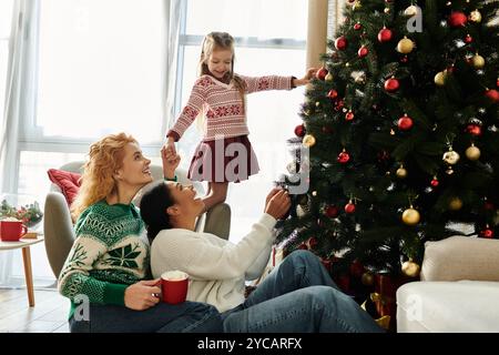 Una coppia amorevole ama decorare il proprio albero con la figlia durante le festività. Foto Stock