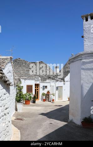 Strada tipica con case di Trulli bianche, tradizionali capanne a secco pugliesi con tetto conico. Alberobello, Italia Foto Stock