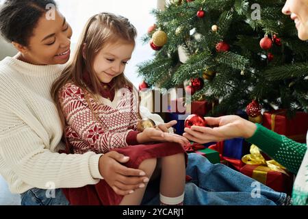 Una coppia amorevole condivide un momento caldo con la figlia mentre decora l'albero di Natale. Foto Stock