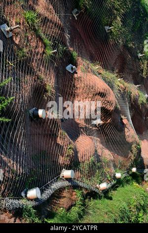 Bulloni da roccia e rete metallica che sostengono scogliere di arenaria rossa instabili sopra la linea ferroviaria a Dawlish, nel Devon meridionale. Foto Stock