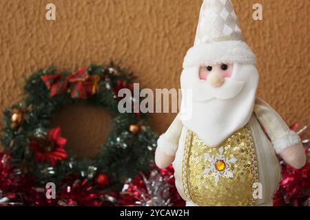 Babbo Natale in feltro imbottito con abito bianco e dorato. Decorazioni natalizie natalizie con ghirlanda sul retro. Foto Stock