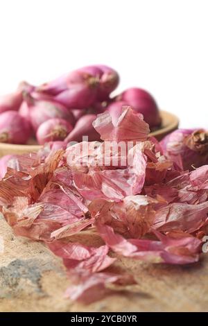 mucchio di buccia di cipolla con scalogno o piccole cipolle rosse sul piano del tavolo, pelle vegetale o rifiuti alimentari utili e benefici Foto Stock