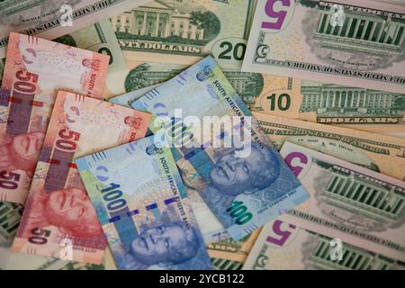 Attenzione selettiva alle banconote sudafricane R50 e R100 con vari tagli di banconote in dollari USA dietro di esse. Foto Stock