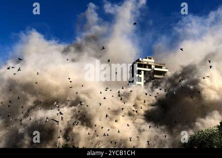 Beirut, Libano. 22 ottobre 2024. I piccioni volano mentre il fumo fuoriesce dal sito, dove gli aerei da guerra israeliani hanno fatto irruzione in un edificio ai margini del sobborgo meridionale di Beirut. Crediti: Marwan Naamani/dpa/Alamy Live News Foto Stock