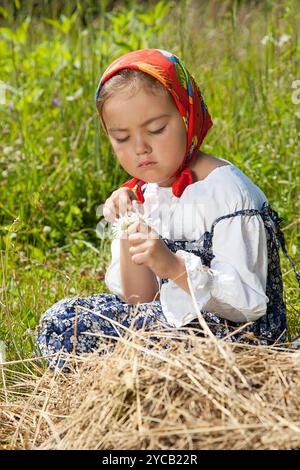 Ritratto all'aperto di una bambina carina con fiori di camomilla in mano Foto Stock