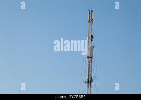 Torre cellulare. Torre cellulare di telecomunicazione contro il cielo azzurro. La struttura è dotata di antenne e cavi utilizzati per trasmettere il terminale mobile Foto Stock