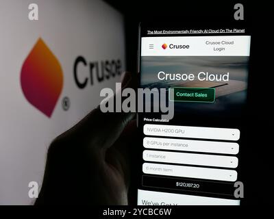 Persona che detiene lo smartphone con la pagina Web della società statunitense Crusoe Energy Systems LLC sullo schermo davanti al logo. Messa a fuoco al centro del display del telefono. Foto Stock