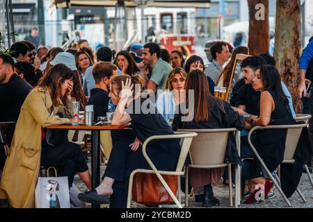 Una vivace caffetteria piena di gruppi di amici impegnati in conversazione e risate mentre sorseggiano un drink a Intendente, Lisbona, Portogallo Foto Stock
