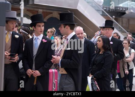 Aspettando in fila per acquistare un biglietto del treno da un distributore automatico. Un gruppo di giovani uomini che si recano al Royal Ascot e indossano cappelli e cappotti. Hanno un aspetto diverso dalla gente comune che fa la fila. Stazione ferroviaria di Waterloo Londra, Inghilterra 22 giugno 2012 2010s Regno Unito HOMER SYKES Foto Stock