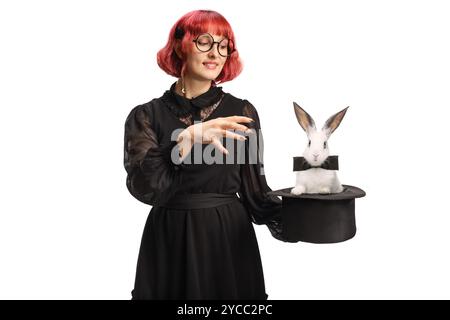 Maga donna con un cappello che esegue un trucco magico con un coniglio isolato su sfondo bianco Foto Stock