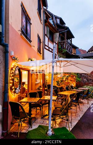 Terrazza con bar e ristorante illuminata. Eguisheim è un comune della Francia nord-orientale situato nel dipartimento dell'Haut-Rhin. Si trova nella storia Foto Stock