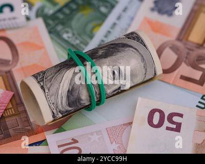 Una pila di banconote da cento dollari che si trovano sullo sfondo delle banconote in euro. Foto Stock