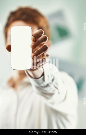 L'uomo d'affari in un ufficio moderno ha uno smartphone con schermo vuoto, perfetto per mostrare app o messaggi. Acquisizione del lavoro aziendale e della comunicazione digitale Foto Stock