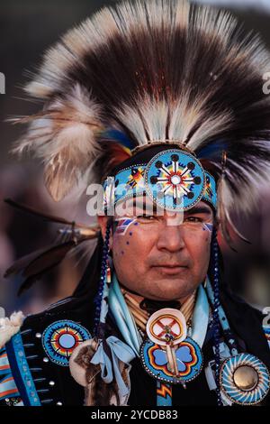 Ritratto di un uomo nativo americano che indossa regalia tradizionali, adornato da vivaci beadwork e un copricapo piumato, che mostra orgoglio culturale Foto Stock