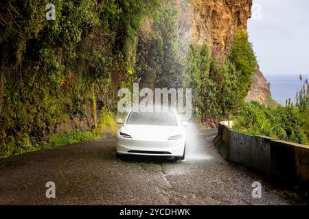 Ponta do Sol, Madeira - 03.10.2024: L'autista guida un'auto elettrica sotto la cascata Cascada dos Anjos, a Ponta do Sol. Isola di Madeira, Portogallo. Foto Stock