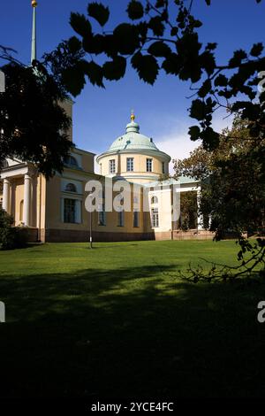 Kotka, Finlandia. 10 agosto 2024 - Chiesa di San Nicola nel parco Isopuisto, incorniciata da foglie in primo piano Foto Stock