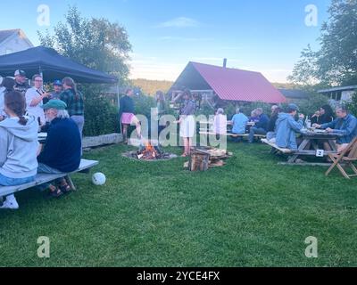 Gente che si gode un fuoco serale sul campo. Presso la panetteria e la pizzeria Tinder Hearth, fienile. A West Brooksville, Down East, Maine, New England, Stati Uniti Foto Stock