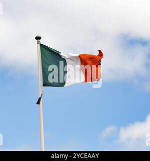 Bandiera nazionale irlandese, tricolore che ondeggia contro un cielo leggermente nuvoloso, Dublino, Irlanda, Europa Foto Stock