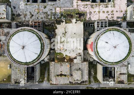 Vista aerea dal drone della centrale nucleare abbandonata e in rovina, torre rotonda del reattore atomico, grande edificio industriale demolito. Foto Stock