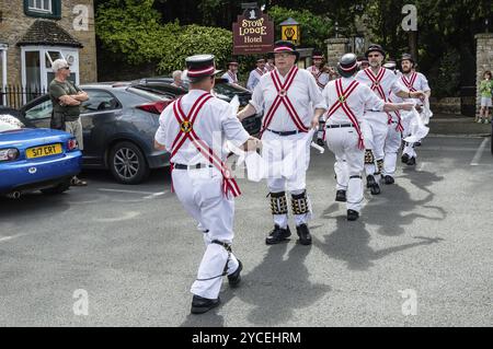 Stow on the Wold, Regno Unito, 12 agosto 2015: I Morris Dancers ballano in una piazza del villaggio di Stow on the Wold nei Cotswolds, mentre alcuni turisti lo sono Foto Stock