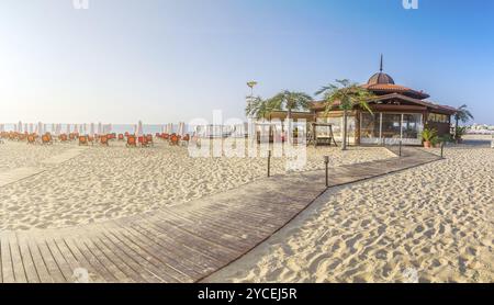 Un bar sulla spiaggia con sedie e ombrelloni su una splendida spiaggia all'alba a Sunny Beach sulla costa del Mar Nero della Bulgaria. Vista panoramica Foto Stock