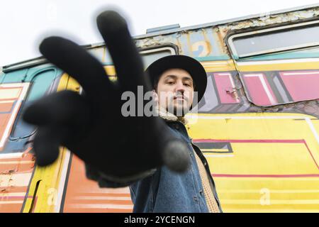 Ritratto di un giovane uomo elegante e affascinante con una giacca in lana denim all'aperto. Un uomo che indossa una giacca di lana di denim e un cappello, guarda la macchina fotografica, un basso Foto Stock