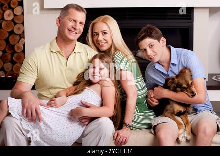 Amabile poisng famiglia in soggiorno come ragazzo giovane detiene il piccolo cucciolo nelle sue braccia Foto Stock