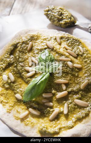 Preparazione della pizza cruda con salsa di pesto Foto Stock