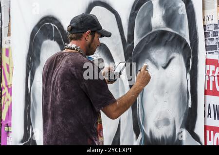 Londra, Regno Unito, 25 agosto 2023: Artista che dipinge graffiti sul muro a Brick Lane a Shoreditch nell'East End Foto Stock
