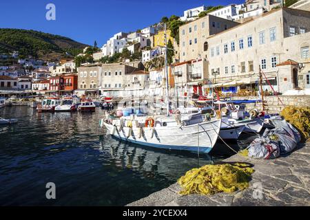 Barche da pesca e da diporto nel porto dell'isola di Hydra. Case della città di Hydra con tetti piastrellati su una ripida collina in una fantastica mattinata d'estate sul greco Foto Stock