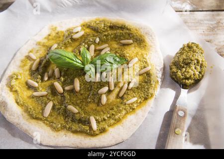 Preparazione della pizza cruda con salsa di pesto Foto Stock