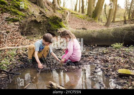 Bambini che giocano in una pozzanghera nella foresta Foto Stock