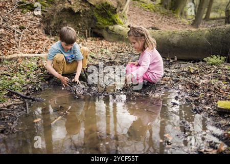 Bambini che giocano in una pozzanghera nella foresta Foto Stock