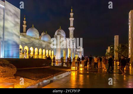 I visitatori nell'area d'ingresso, la moschea dello sceicco Zayed nell'illuminazione serale, la grande moschea, Abu Dhabi, Emirati Arabi Uniti, Asia Foto Stock