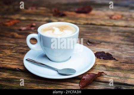 Una tazza di caffè su un tavolo di legno con foglie d'autunno marroni. Primo piano. Foto Stock