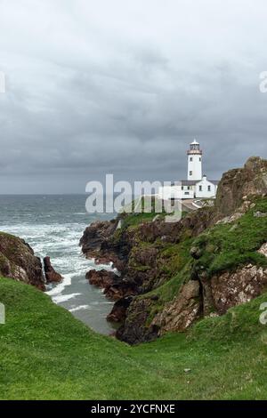 Ripresa verticale del Faro di Fanad Head nella contea di Donegal, Irlanda, durante una tempesta. Il faro sorge su aspre scogliere contro il turbolento oceano Foto Stock