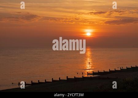 Inghilterra, Kent, Herne Bay, Sunrise Over Sea e Beach Groynes Foto Stock