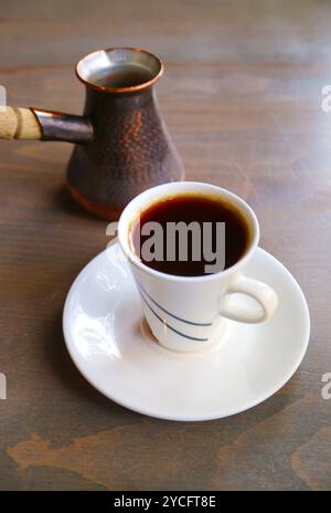 Tazza di caffè turco caldo con caldaia servita su un tavolo di legno Foto Stock