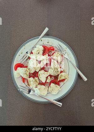 Mozzarella condita con pomodori e 3 forchette su un piatto bianco come antipasto per tre persone Foto Stock