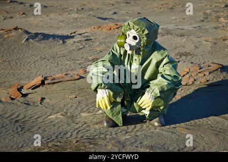 Scienziato in tuta protettiva e maschera antigas seduta sulle scorie Foto Stock