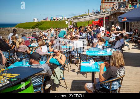 I vacanzieri si godono il sole estivo seduto sulla terrazza all'aperto del Fistral Beach Bar di Newquay in Cornovaglia nel Regno Unito. Foto Stock