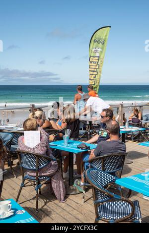 I vacanzieri si godono il sole estivo seduto sulla terrazza all'aperto del Fistral Beach Bar di Newquay in Cornovaglia nel Regno Unito. Foto Stock